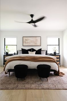 a bedroom with a bed, two chairs and a ceiling fan