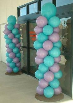 two tall blue and purple balloons in front of a building