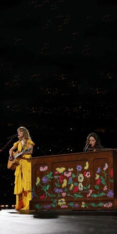 two women in yellow dresses are on stage