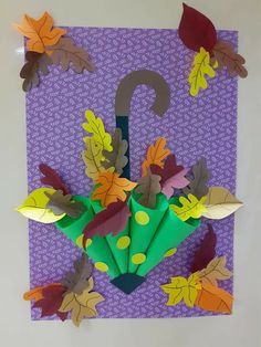 an umbrella made out of paper sitting on top of a purple background with leaves and dots