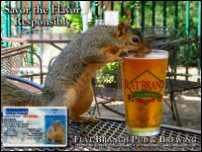 a squirrel sitting on top of a metal table next to a glass filled with liquid