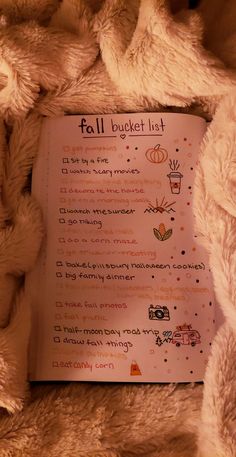 a white teddy bear laying on top of a bed next to a sign that says fall bucket list