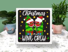 a christmas wine crew card sitting on top of a table next to potted plants