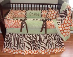 a baby crib bedding set with an orange and brown zebra print, name on it