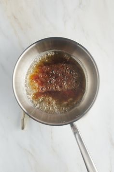 a frying pan filled with food on top of a white marble countertop next to utensils