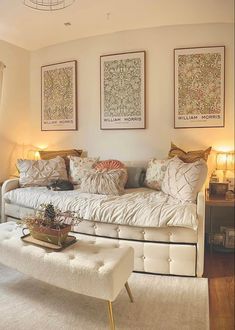 a white day bed sitting in a living room next to two pictures on the wall