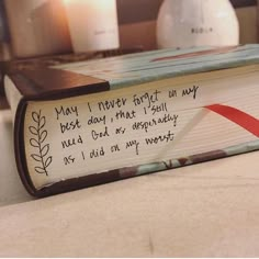 an open book with writing on it sitting on a table next to candles and other items