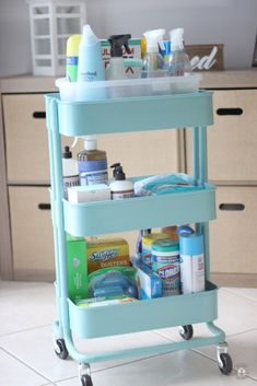 a blue cart filled with cleaning products on top of a kitchen floor