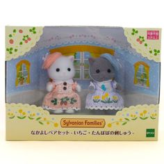 two hello kitty dolls sitting in front of a doll house