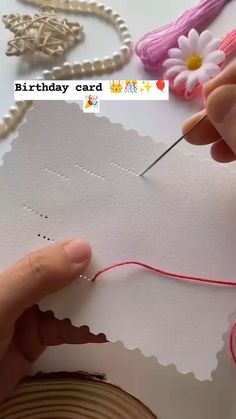 someone is making a birthday card out of paper and thread with a flower on it