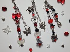 several charms are displayed on a white surface with red and black beads in the shape of hearts