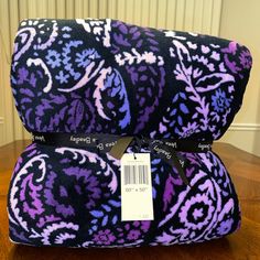 a purple and black blanket with a price tag on the front, sitting next to a white background