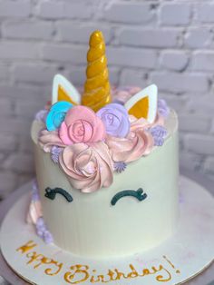 a birthday cake decorated with an unicorn's face and flowers