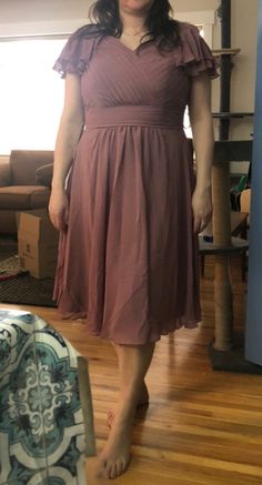 a woman in a dress standing on a hard wood floor