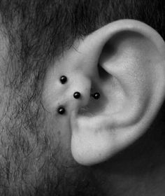 a man's ear with three small black studs on the top of it