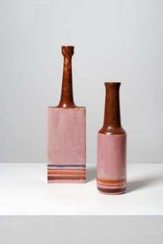 two pink vases sitting next to each other on top of a white countertop