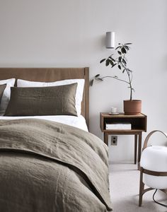 a bed sitting next to a table with a potted plant on it