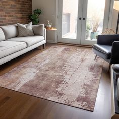 a living room filled with furniture and a large rug on top of a hard wood floor