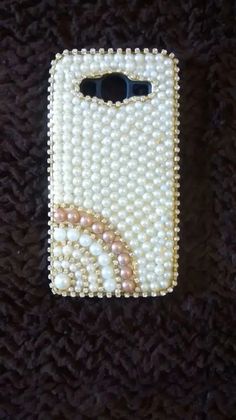 a cell phone covered in pearls on a black surface