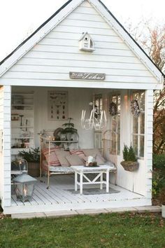 a white shed with lots of plants and furniture