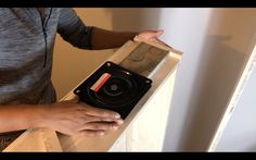 a person holding a speaker in front of a box with its lid open and it's inside