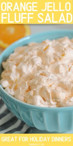 an orange jello fluff salad in a blue bowl on a striped tablecloth