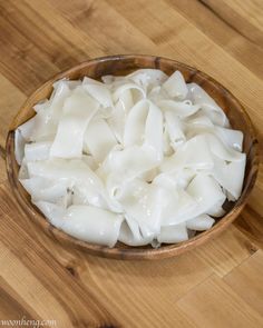 a wooden bowl filled with dumplings on top of a wooden table