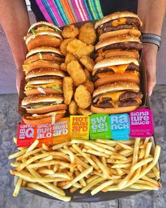 a tray filled with lots of different types of burgers and fries on top of each other