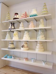 a shelf filled with lots of different types of cakes on top of white shelving