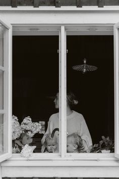 black and white photograph of woman looking out the window with baby in her lap,