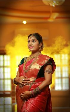 a woman in a red and green sari standing with her hands on her hips