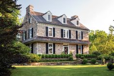 a large stone house with black shutters on the front and side windows is shown