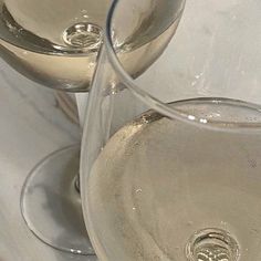 two wine glasses sitting next to each other on a white table cloth covered tablecloth