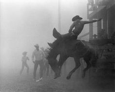 a man riding on the back of a horse while other people watch from behind it