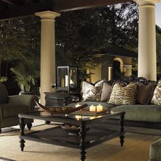 a living room filled with lots of furniture next to a swimming pool in the evening