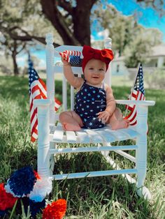 Smiley Baby girl in a navy blue shirt and tank top outfit with white stars and an oversized red bow sitting in a white rocking chair in front of a tall big tree with USA flags and red white and blue flowers 4th Of July Pics, Baby Holiday Photos, 4th Of July Photography, Diy Newborn Photography, 4th Of July Photos, Baby Milestones Pictures, Monthly Baby Pictures, Monthly Pictures, Monthly Baby Photos