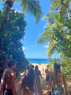 people walking on the beach with palm trees in the foreground and blue water in the background