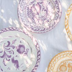 three plates sitting on top of a table covered in purple and yellow designs next to each other