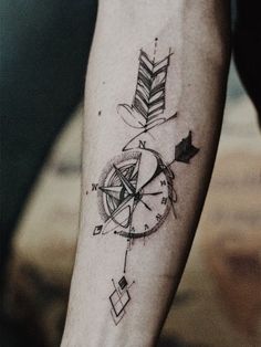 a person with a tattoo on their arm has a compass and an arrow in it