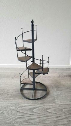 a metal and wood spiral staircase on the floor in an empty room with white walls