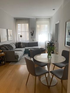 a living room filled with furniture and a white table surrounded by gray chairs next to a couch