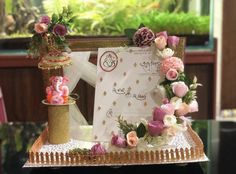 a table topped with a cake and flowers on top of a wooden tray next to a card