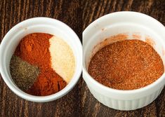 two white bowls filled with different colored spices on top of a wooden table next to each other