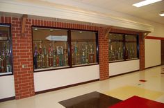 an empty room with several glass cases on the wall and red mats on the floor