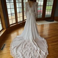 a white wedding dress on display in front of large windows with wooden floors and wood flooring