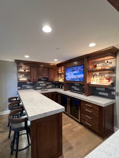 a large kitchen with wooden cabinets and marble counter tops, along with bar stools