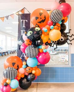 a bunch of balloons that are in the shape of cats and pumpkins with faces on them