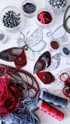 various beads and threads are arranged on a table with butterfly shaped objects in the background