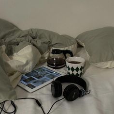 headphones, coffee mug and tablet on a bed