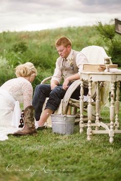 a man and woman sitting on top of a wooden bench next to each other in the grass